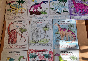 Obrazki z dinozaurami pokolorowane przez dzieci z wykorzystaniem mazaków i kredek.